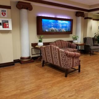 A cozy lobby area featuring a sofa, decorative aquarium, and plants.