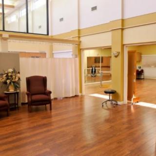A spacious dance studio with hardwood floors, mirrors, and comfortable seating.