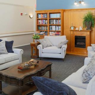 A cozy living room with comfortable seating, a wooden coffee table, bookshelves, and a fireplace.