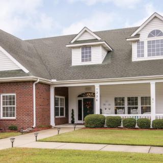 A beautiful suburban home with a spacious front porch and well-maintained lawn.