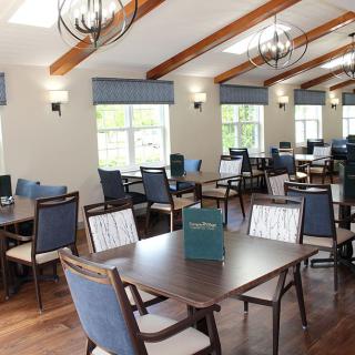 A modern dining room with tables and chairs arranged neatly under stylish lighting.
