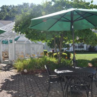 A sunny outdoor patio area with tables, chairs, and umbrellas.