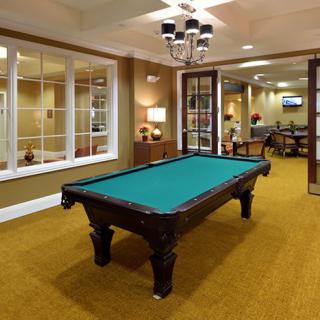 A well-furnished game room featuring a pool table under elegant lighting.