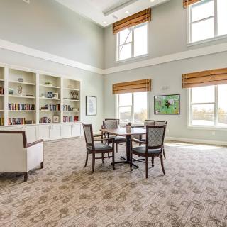 A spacious library room with large windows and elegant furnishings.