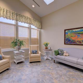 A cozy living room with armchairs, a sofa, and decorative plants under natural light.