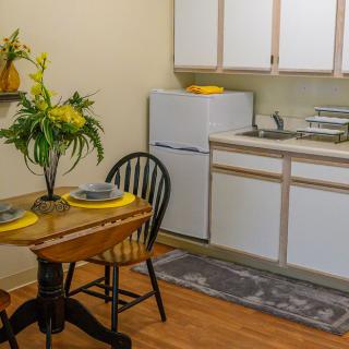 A compact kitchen and dining area featuring a small table set for two, with decorative flowers.