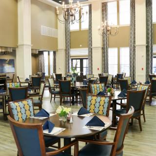 A spacious dining room with elegantly set tables and large windows.
