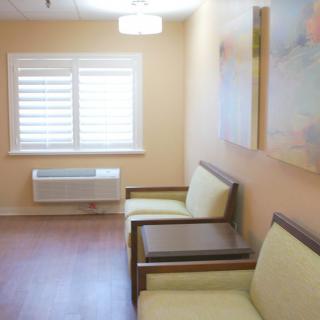 A simple waiting room with chairs and artwork on the wall.