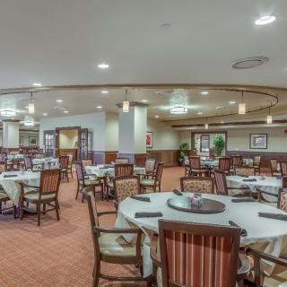 A spacious dining area with neatly arranged tables and chairs, featuring elegant decor and warm lighting.