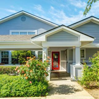 A charming residential house with a red door and landscaped garden.