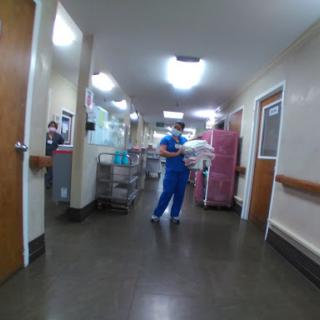 A nurse in scrubs navigates through a hospital corridor, carrying supplies.