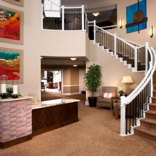 A modern lobby featuring a grand curved staircase, reception desk, comfortable seating, and vibrant artwork on the walls.
