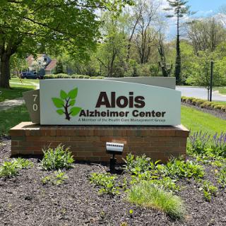Entrance sign of the Alois Alzheimer's Center, surrounded by greenery.