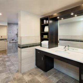A modern bathroom with a sleek sink, large mirror, and tiled flooring.