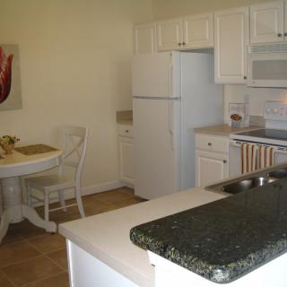 A cozy kitchen with white cabinetry and a small dining area.