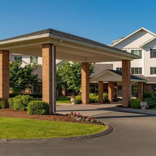 A welcoming building entrance with well-maintained landscaping and a covered driveway.