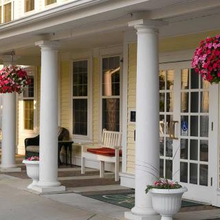 A welcoming porch with white columns and hanging flower baskets.
