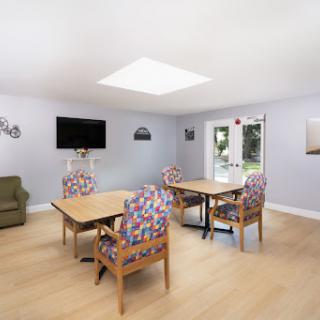 A bright and inviting living space featuring colorful chairs and a television, perfect for leisure and social gatherings.