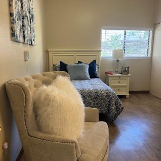 A cozy bedroom featuring a comfortable bed, stylish armchair, and natural light from the window.