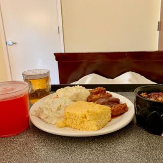 A well-presented meal featuring rice, cornbread, and meat, accompanied by refreshing drinks.