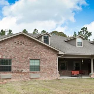 A suburban brick house with a spacious yard and covered porch.