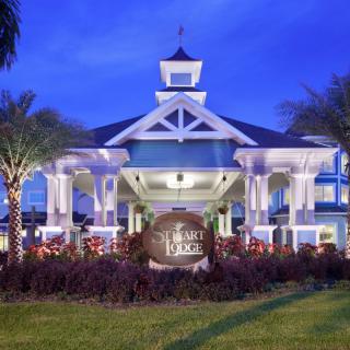 A beautifully lit resort entrance at night with palm trees and elegant architecture.
