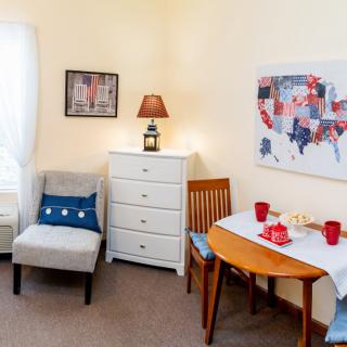 A cozy living room with a small table set, comfortable seating, and wall art featuring a map.