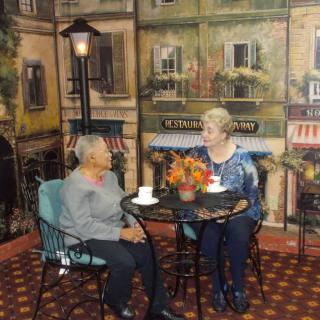 Two elderly women enjoying a conversation in a cafe setting.