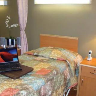 A cozy bedroom with a single bed, floral bedding, and a laptop on the bed.