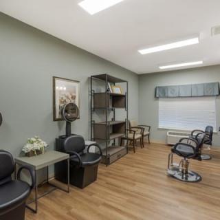 A modern salon interior with chairs, hair dryers, and shelving units.