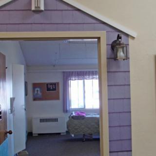 A room with purple walls, featuring a hospital bed and a window.