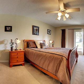 A cozy bedroom featuring a wooden bed frame, nightstand, and ceiling fan.