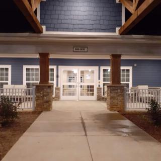 A well-lit building entrance at night with a porch and columns.