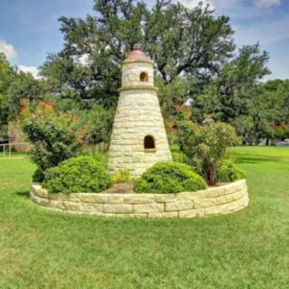 A small decorative lighthouse surrounded by greenery in a park.