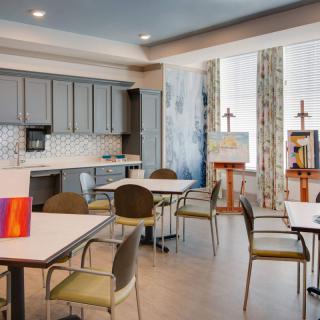 A modern kitchen and dining area with several tables and chairs, featuring contemporary decor and ample lighting.