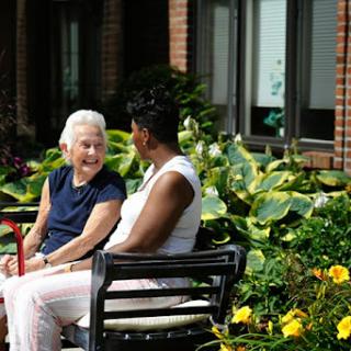 Two women enjoying a warm conversation in a vibrant garden.