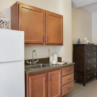 A small kitchen area with wooden cabinets, a sink, and a refrigerator.