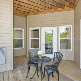 A cozy outdoor patio with a small table, two chairs, and a vase of flowers on a wooden deck.