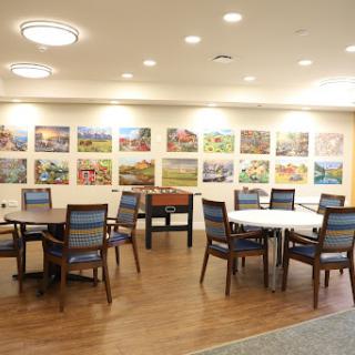 A cozy dining area featuring several tables and chairs, adorned with vibrant artwork on the walls.
