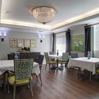 A spacious dining room with elegantly set tables, comfortable chairs, and a chandelier providing ambient lighting.