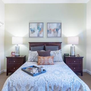 A well-decorated bedroom with matching nightstands and lamps, featuring a neatly made bed with a decorative tray.
