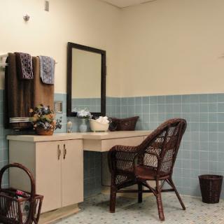 A cozy bathroom vanity setup featuring a mirror, chair, and neatly arranged towels.