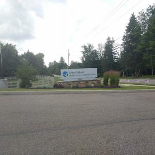 A business sign set against a backdrop of trees by the roadside.