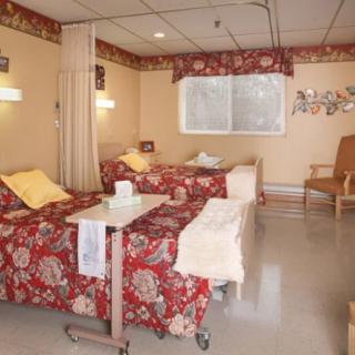 A hospital room with two patient beds and seating area.