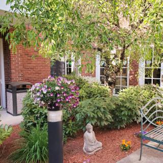 A serene garden space featuring lush greenery, colorful flowers, and a peaceful statue.