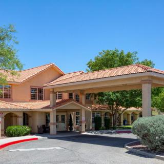 A building with a covered entrance surrounded by trees under a clear blue sky.