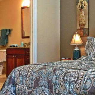 A cozy bedroom with a patterned bedspread and a view into the adjoining bathroom.