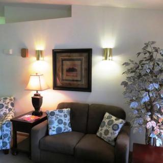 A cozy living room with a sofa, decorative cushions, a floor lamp, and wall sconces.