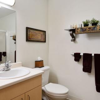 A neat and tidy bathroom with a sink, toilet, mirror, towels, and decorative elements.