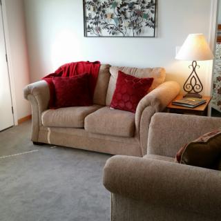 A cozy living room with a beige sofa, red cushions, and a decorative lamp.